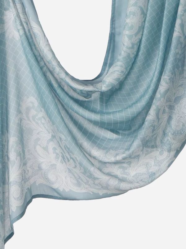Hijab en coton imprimé bleu baroque, drapé en plis, fond bleu opale grisé, volutes blanches et fin treillis losangé