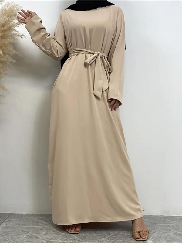 Une femme porte une abaya beige simple avec des manches longues et un hijab noir