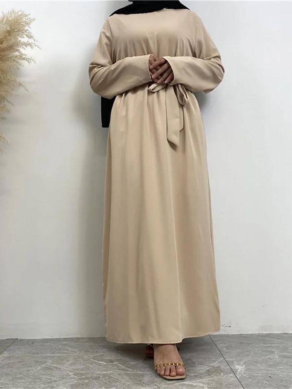 Une femme porte une abaya beige avec une ceinture nouée et un hijab noir