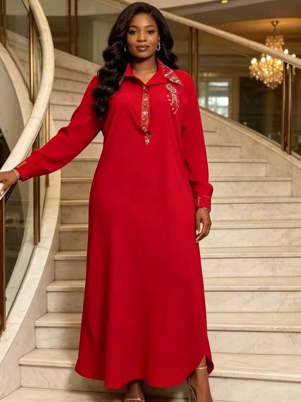Abaya col chemise rouge Rubis de Marrakech portée de face dans un escalier en marbre, col, patte et poignets ornés de strass