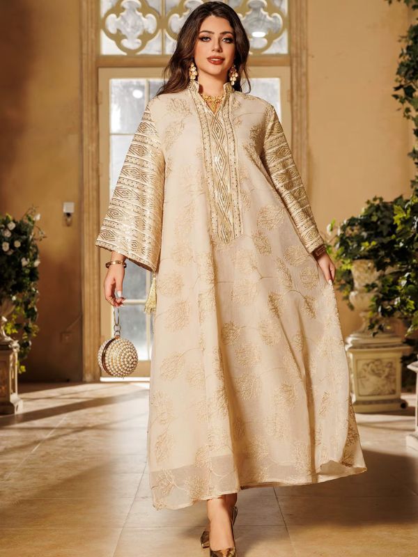 Une femme porte une abaya dorée à motifs floraux dans un décor raffiné