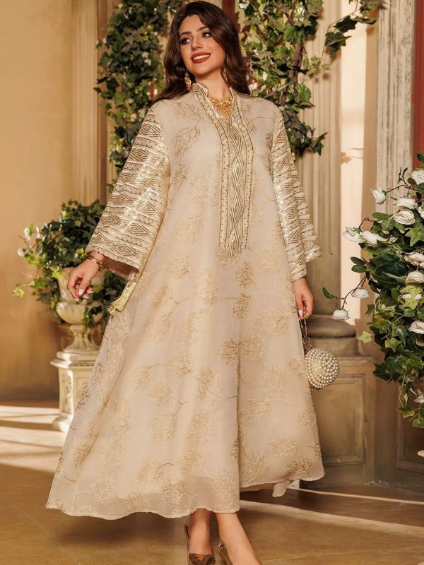 Une femme porte une abaya dorée à motifs floraux dans un décor raffiné