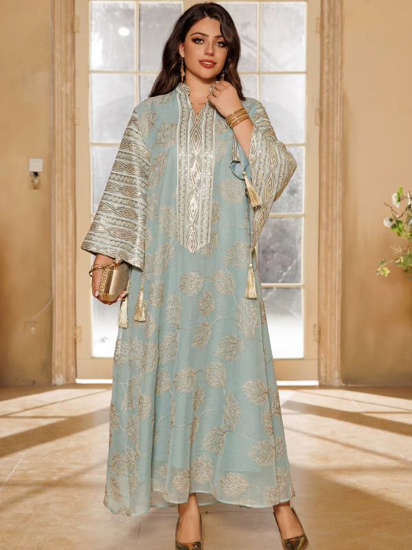 Une femme pose debout en abaya fluide bleu pastel à motifs floraux