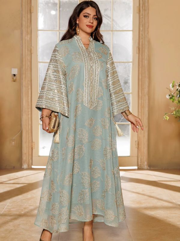 Une femme habillée d’une abaya bleu ciel brodée tient une pochette dorée