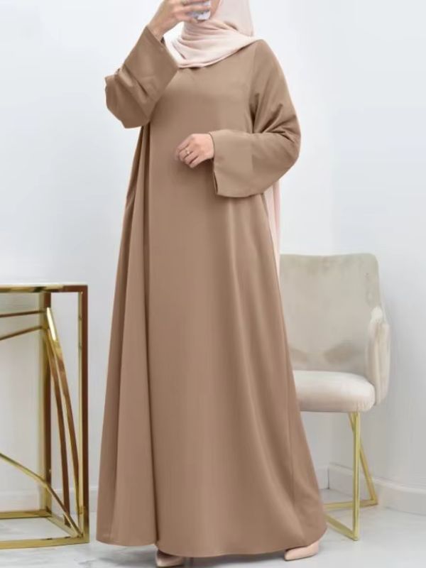 Une femme porte une abaya beige sable et se prends en photo