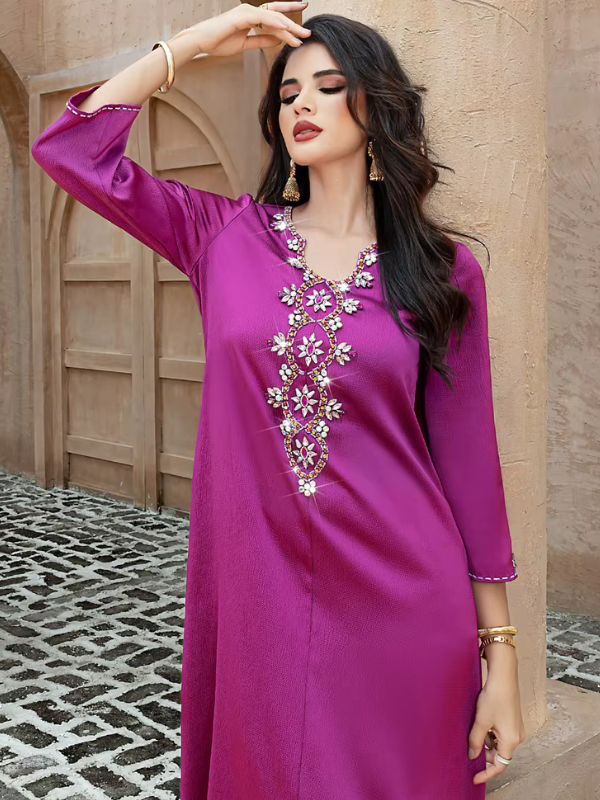 Abaya Dubaï fuchsia, gros plan, bras relevé au-dessus de la tête, manche évasée bordée d'un point blanc et de strass, bande de fleurs sur le devant
