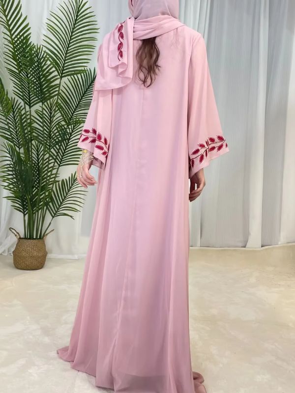 Une femme se tient de dos et porte une abaya dubai rose