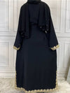 Une femme porte une abaya noire et se tient de dos