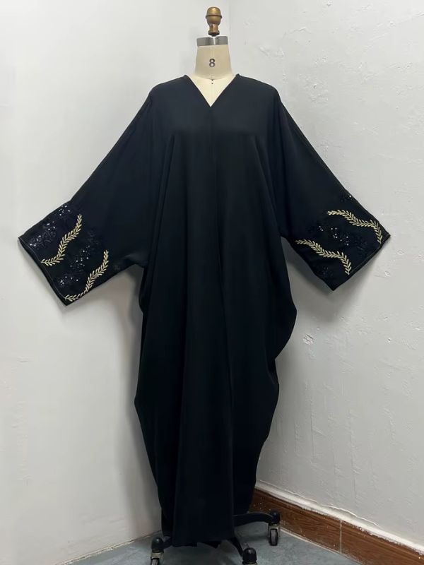Mannequin affichant une abaya noire ample aux manches décorées de broderies dorées