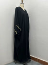 Mannequin de profil portant une abaya noire avec broderies dorées discrètes sur les manches