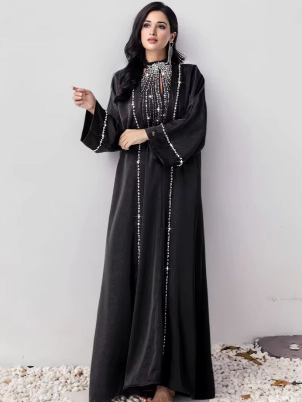 Femme en abaya noire chic, décorée de strass du col aux poignets