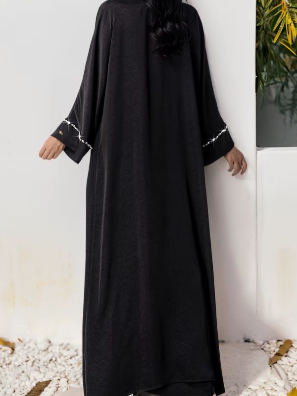 Vue arrière d’une abaya noire longue portée dans un décor épuré