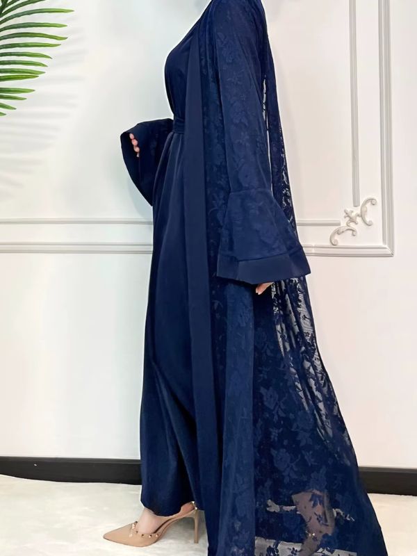Une femme se tient de profil et porte une abaya dubai de luxe bleu saphir en dentelle