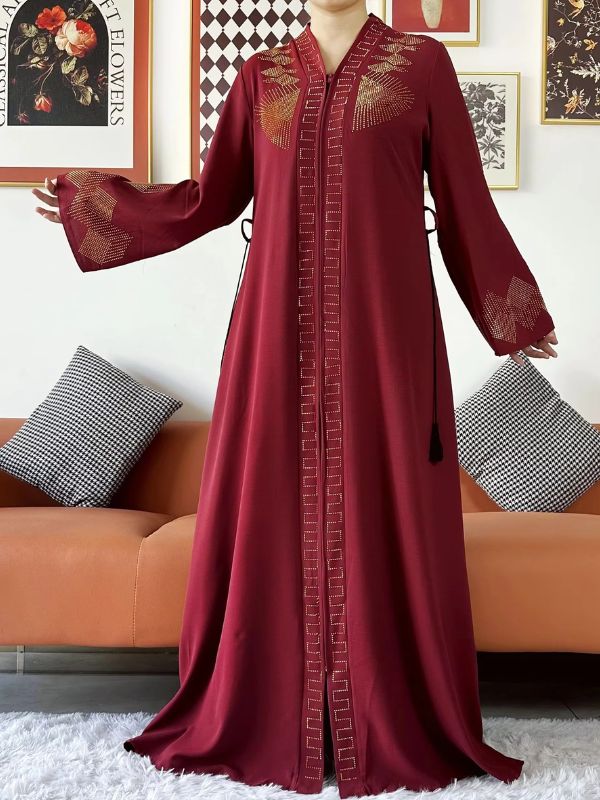 Une femme porte une abaya de luxe bordeaux