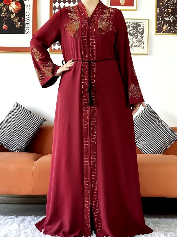 Une femme porte une abaya de luxe bordeaux