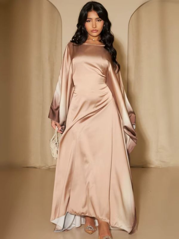 Une femme vêtue d’une abaya fluide en satin beige doré aux manches amples dégradées marron