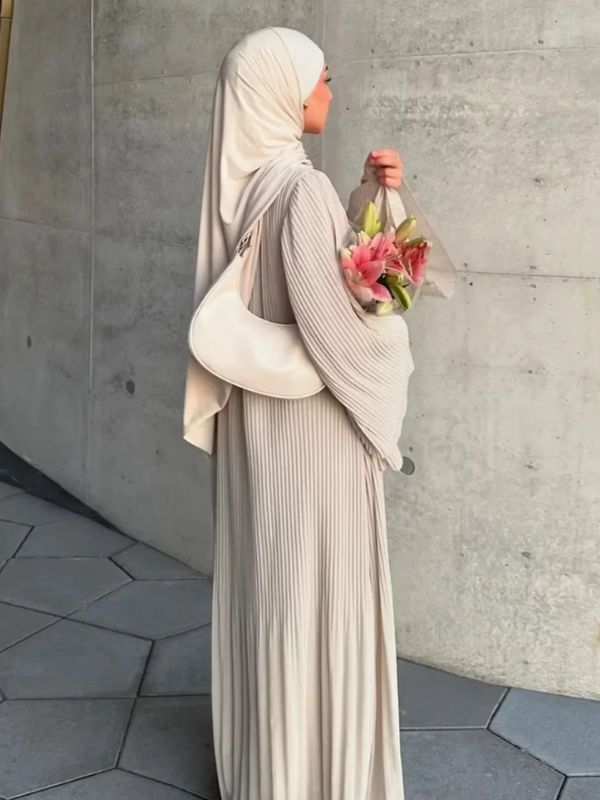 Une femme de dos porte une abaya beige
