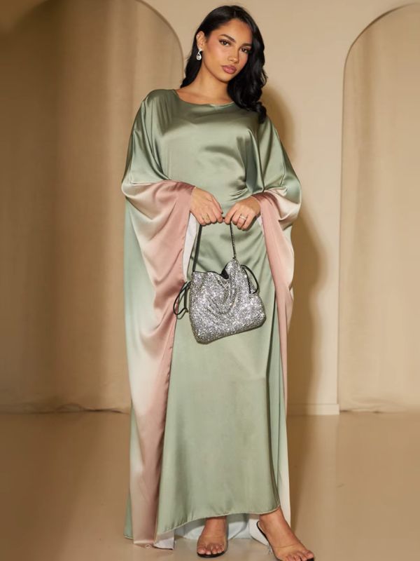 Une femme vêtue d’une abaya fluide en satin vert clair aux manches amples dégradées rose, posant de face