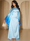 Une femme vêtue d’une abaya fluide en satin bleu ciel aux manches amples dégradées bleu roi, posant de face
