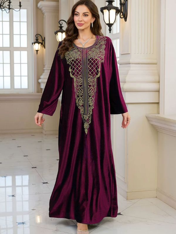 Abaya Dubaï en velours bordeaux, vue de face, bras le long du corps, robe ample jusqu'au sol et plastron brodé doré