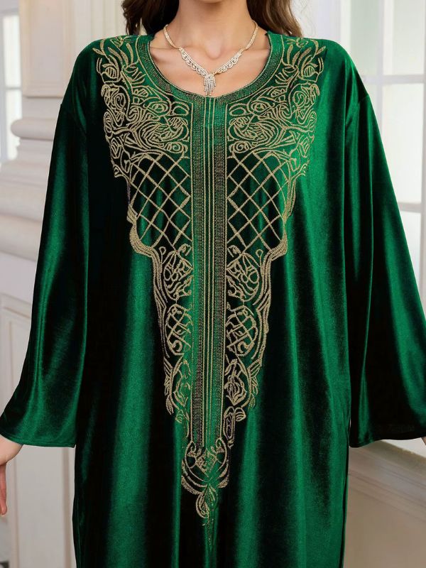 Abaya Dubaï en velours vert émeraude, gros plan sur le plastron brodé de fils dorés : treillis de losanges, volutes et bande centrale de fines lignes