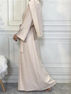 Femme musulmane de profil qui porte une abaya kimono dubai beige  dans un intérieur luxueux