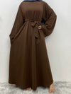 Femme qui porte une abaya kimono marron en se tenant la hanche avec sa main