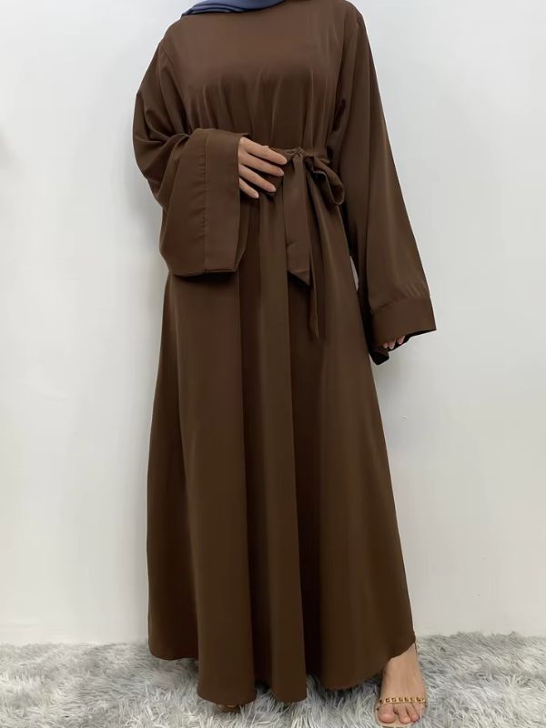 Femme qui porte une abaya kimono marron en se tenant la hanche avec sa main