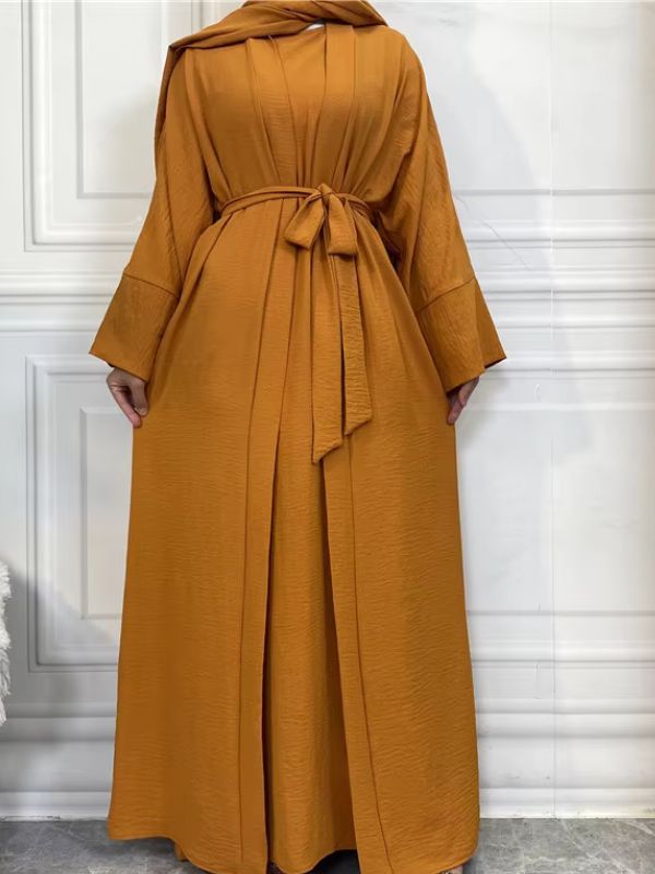 Femme qui porte une abaya kimono très ample de couleur ocre, avec une ceinture à la taille