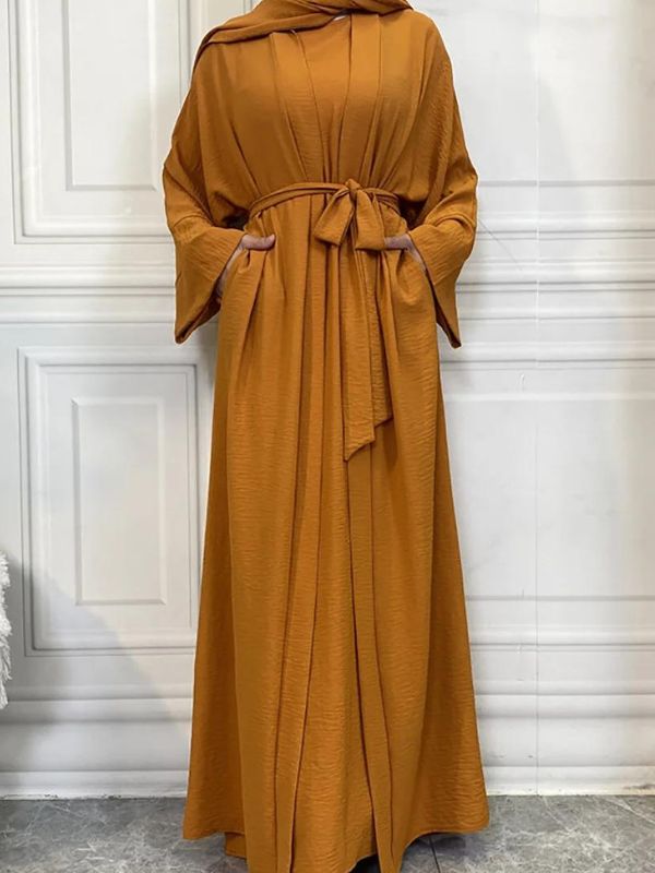 Femme qui porte une abaya kimono très ample de couleur ocre, avec une ceinture à la taille