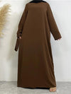 Une femme pose en portant une abaya marron foncé ample et longue