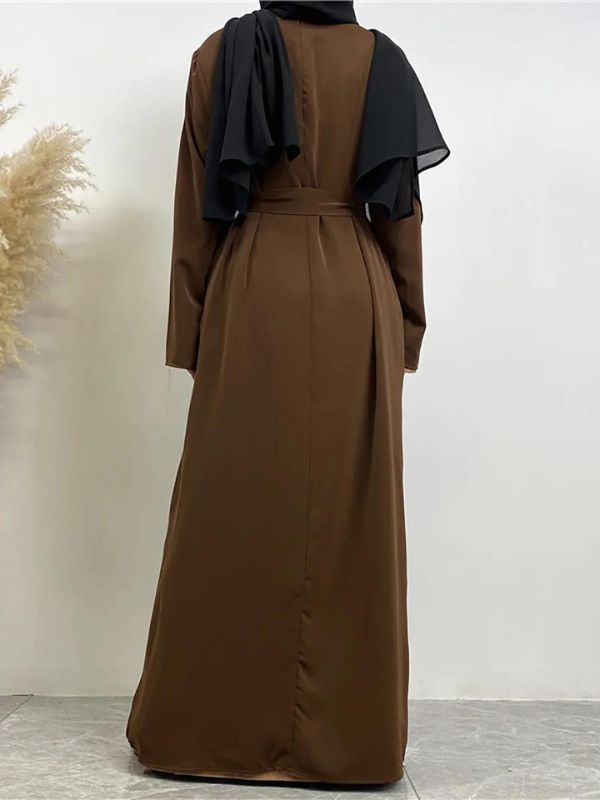 La femme est vue de dos, portant une abaya marron foncé qui tombe jusqu&#39;au sol