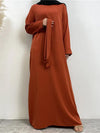 La femme porte une abaya longue de couleur orange vif, vue de face