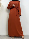 La femme porte une abaya longue de couleur orange vif, vue de face