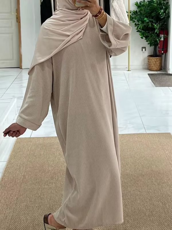 Une femme en abaya velours de couleur beige