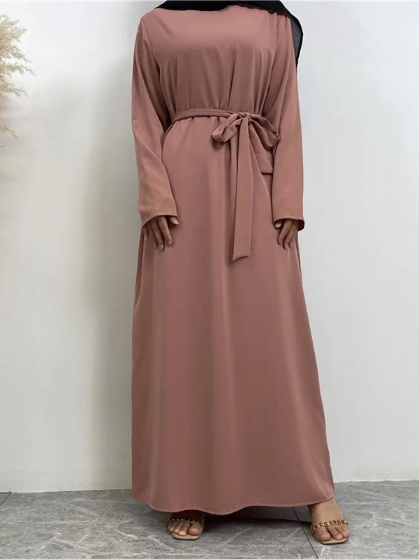 Une femme en abaya rose poudré avec une ceinture nouée à la taille et un hijab noir