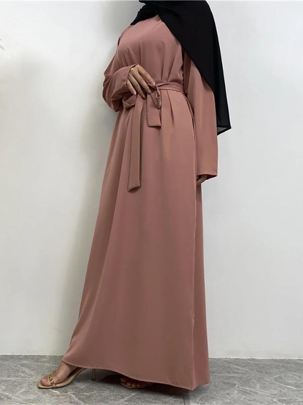 Vue latérale d&#39;une femme portant une abaya rose poudré ceinturée avec un hijab noir