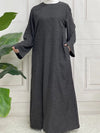 Une femme porte une abaya en satin gris