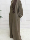 Une femme de profil en abaya en satin marron