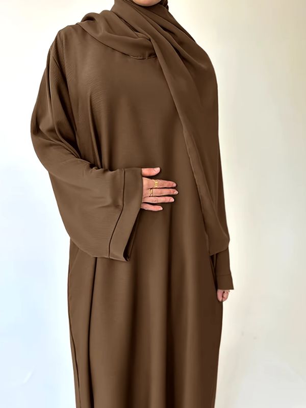 Une femme porte une sublime abaya en satin marron