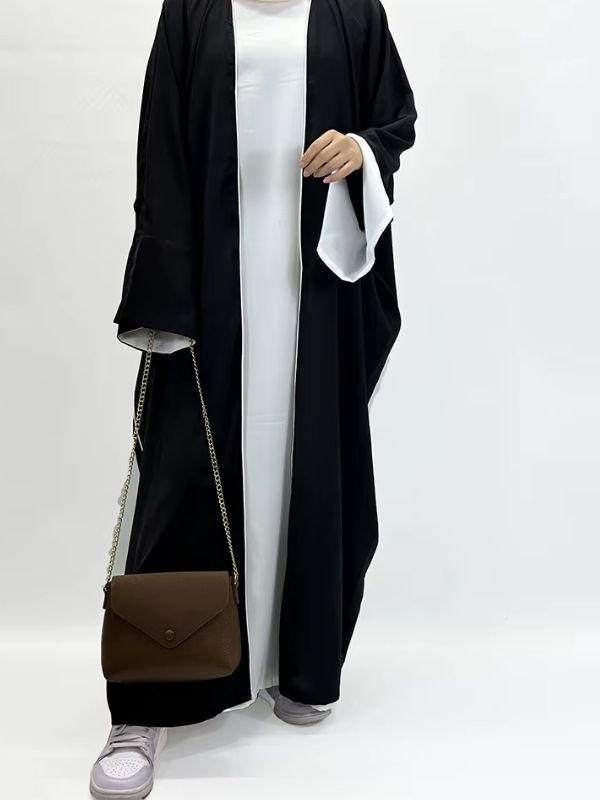 Une femme portant une abaya kimono noire en satin ouverte