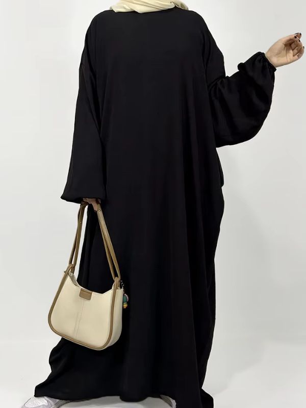 Une femme porte une abaya noire en matière de crêpe jazz