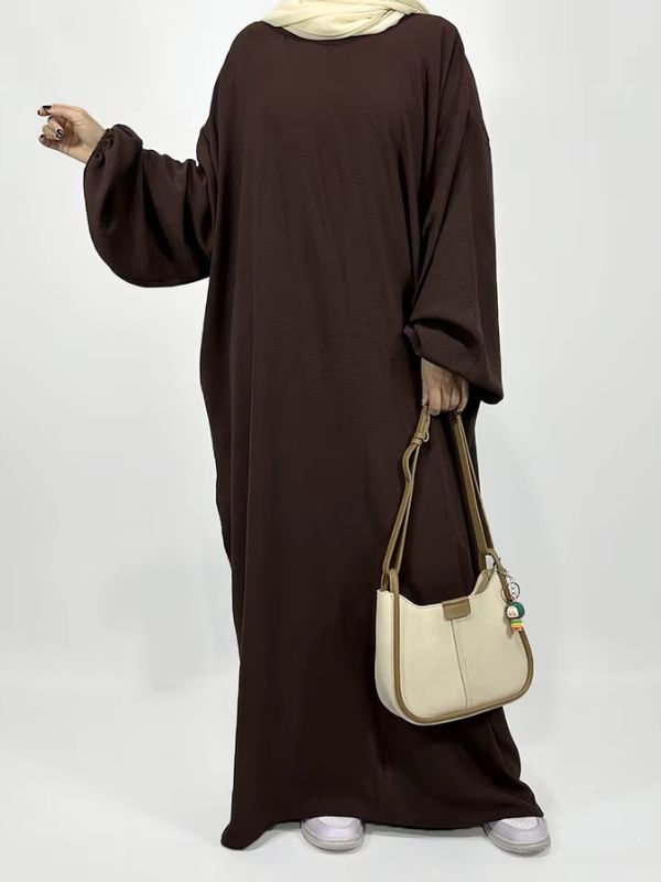 Une femme porte une abaya chocolat avec un hijab beige