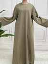 Une femme porte une abaya en satin taupe