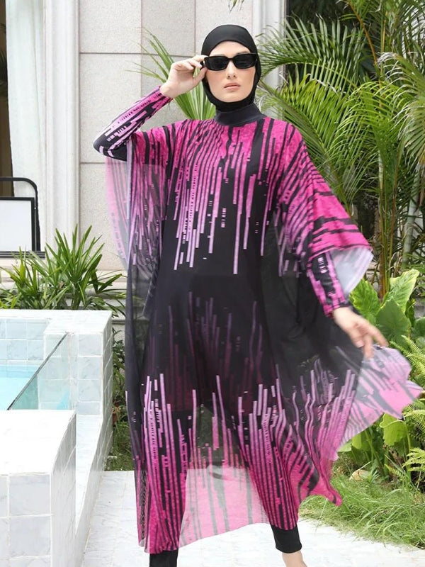 Une femme est vêtue d'un burkini noir orné de motifs roses éclatants qui se prolongent sur une cape fluide transparente, créant un effet élégant et dynamique. Elle porte des lunettes de soleil noires, ajoutant une touche chic à son look. L'ensemble de sa tenue est harmonieux, et elle se tient près d'une piscine entourée de végétation luxuriante, ce qui accentue l'élégance naturelle de son apparence