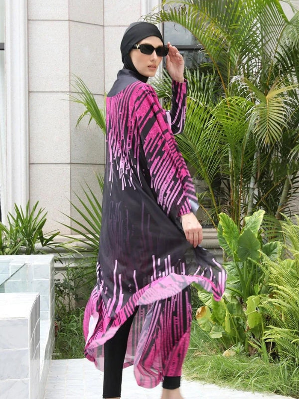 Une femme est vêtue d'un burkini noir orné de motifs roses éclatants qui se prolongent sur une cape fluide transparente, créant un effet élégant et dynamique. Elle porte des lunettes de soleil noires, ajoutant une touche chic à son look. L'ensemble de sa tenue est harmonieux, et elle se tient près d'une piscine entourée de végétation luxuriante, ce qui accentue l'élégance naturelle de son apparence