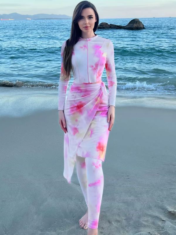 Une femme portant un burkini aux motifs tie-dye rose et blanc, debout face à la mer