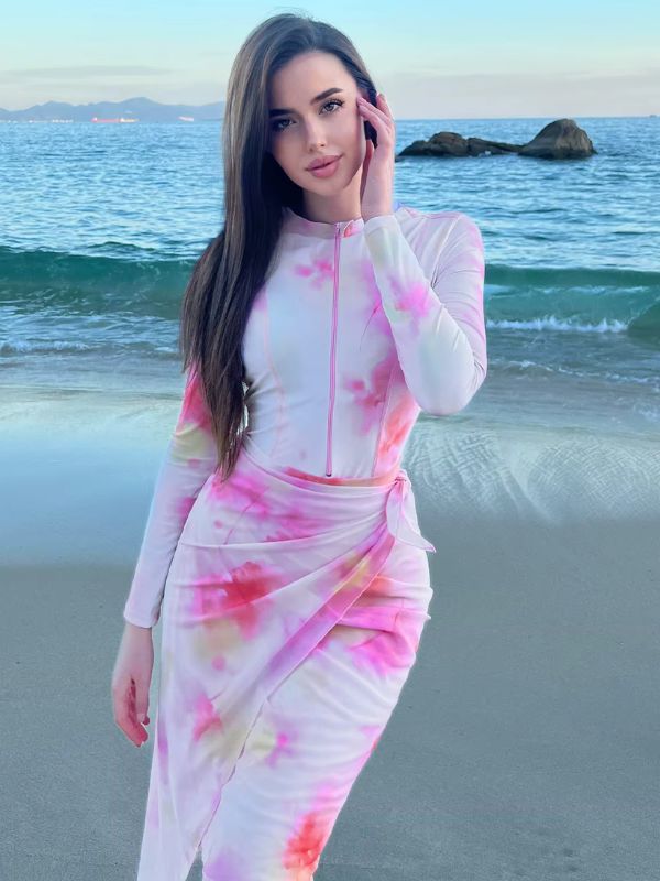 Une femme portant un burkini aux motifs tie-dye rose et blanc, debout face à la mer