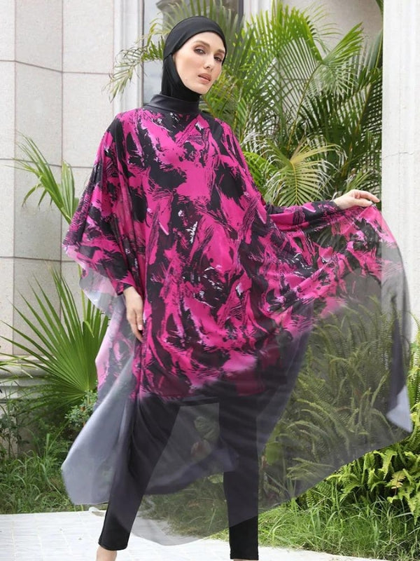 Une femme porte un burkini noir et rose avec des motifs abstraits éclatants. Une cape fluide et transparente assortie, flottant légèrement autour d'elle, ajoute une touche dramatique et élégante à sa tenue. La posture de la femme met en valeur le mouvement de la cape, créant un effet visuel de légèreté et de dynamisme dans un cadre urbain sophistiqué, entouré de verdure. L'ensemble offre un contraste saisissant entre les teintes sombres et vibrantes, soulignant à la fois l'élégance et la modernité