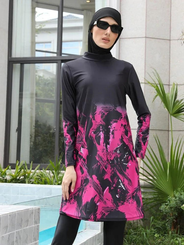 Une femme porte un burkini noir avec des motifs abstraits en rose vif qui s'étendent sur toute la longueur de la tunique. Le voile noir assorti encadre son visage, ajoutant une touche d'élégance à l'ensemble. La tenue est mise en valeur par un cadre extérieur verdoyant, avec des plantes luxuriantes en arrière-plan, qui contraste joliment avec les couleurs vives du burkini